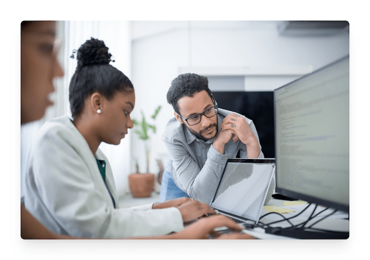 people working on laptop and looking at computer monitor